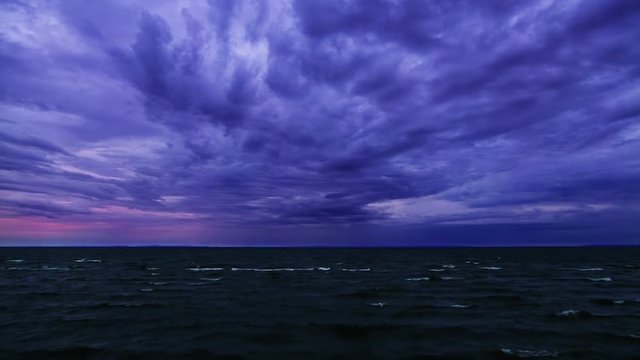 Loop displays a colorful story sky near dawn with waves, whipped up by the Lake Superior winds, coming in to shore. 