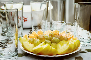 a lot of fruit on a plate. Apple, tangerine, grapes.