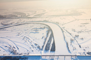 Train crossing river on bridge in winter, top view
