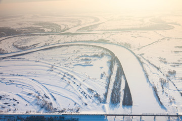 Train crossing river on bridge in winter, top view