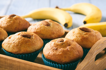 Sweet banana muffins with almond on blue wooden table.