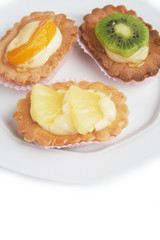 Tortine alla crema e frutta su piatto su sfondo bianco
