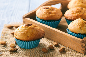Sweet muffins with almond on blue wooden table.