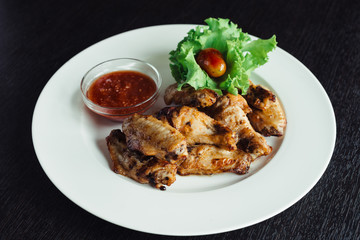 Chicken wings with sauce on plate on wooden table