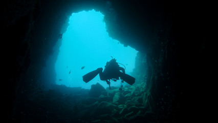 Fototapeta na wymiar Scuba diver swimming up underwater tunnel