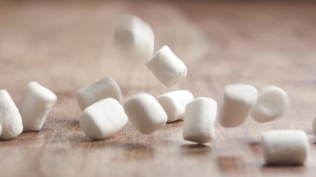 Slow motion of white marshmallow falling on wood table, 180fps prores footage