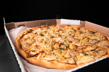 Pepperoni in the box on the black background. Taste