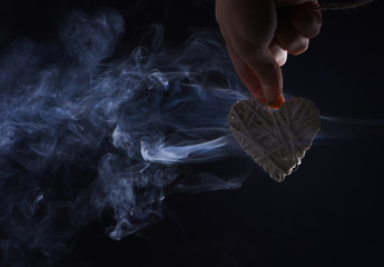 male hand with decorative valentines day heart in smoke