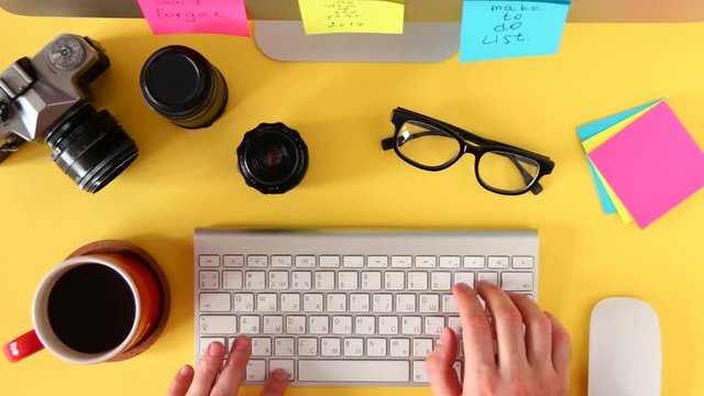 Top view of workplace photographer. A man working at a computer. The items are laid out in the spirit of perfectionism on a wellow background.
