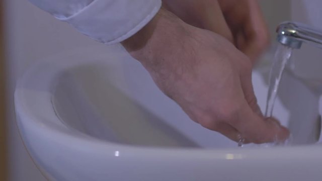 The doctor in a military hospital thoroughly wash their hands before surgery. Slow motion