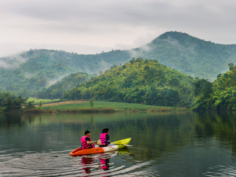 Tourists on the cayak  in beautiful lake and foggy mountain