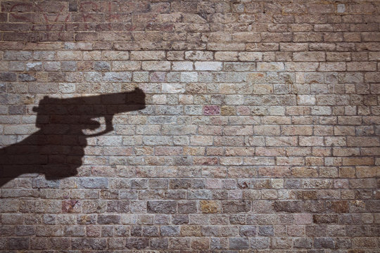 hand holding a gun silhouette on brick wall