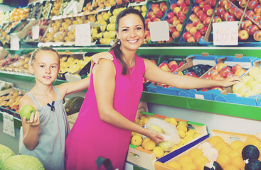 woman with girl buying apples