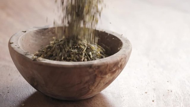 Slow motion of provence herbs falling in wood bowl on wooden table, 180fps prores footage