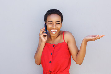 smiling african woman talking on cell phone with hand raised