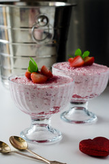 Strawberry mousse in a glass dish decorated with strawberry and lemon balm.
