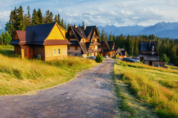 Traditional wooden house in the mountains on a green field road 
