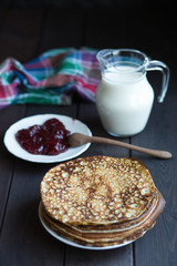 Homemade pancakes with raspberry jam on a dark wooden table. Shrove Tuesday