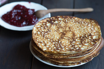 Homemade pancakes with raspberry jam on a dark wooden table. Shrove Tuesday