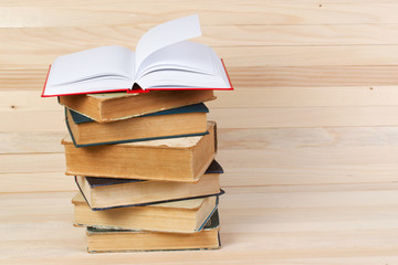 Open book, stack of hardback books on wooden table. Back to school. Copy space