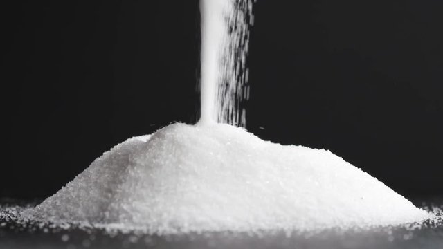 Slow motion of pile of white sugar falling on slate background, 180fps prores footage