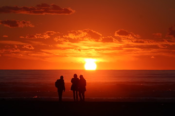 Fototapeta na wymiar persone che ammirano il tramonto in spiaggia