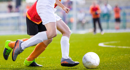Fototapeta premium Soccer Players Running After the Ball on the Pitch. Football Match Between Two Teams. Outdoor Sports Competition
