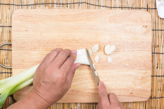 Chef cutting scallion on wooden broad