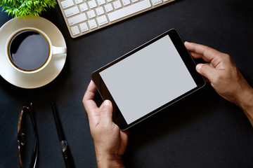 Modern dark surface office desk table with computer, Tablet with blank screen  and cup of coffee. Hero Header Concept.