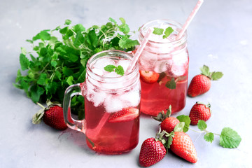 Strawberry lemonade with ice and mint in glass mug jars