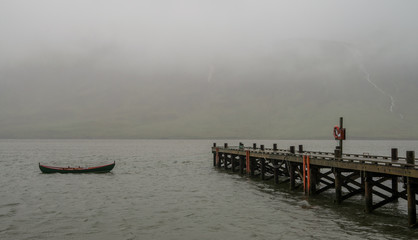 Isolated boat and dock in misty sea landscape 