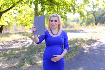 Good-Looking Pregnant Girl Holds Tablet And Talks on Skype, Welc