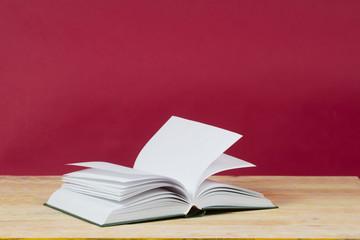 Open book on wooden table. Back to school. Red background. Copy space