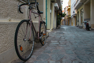 Fototapeta na wymiar Parked vintage old bicycle from the street greek island town panorama