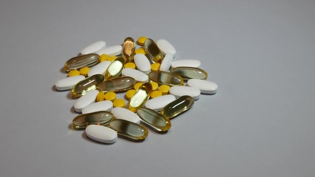 Mixed natural food supplement pills omega 3 calcium,magnesium and vitamin B capsules on grey background