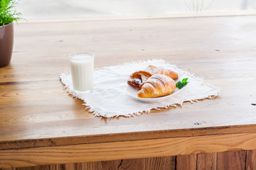 Served breakfast with assortment of fresh pastries and glass of milk on the cafe table at the viewing window. Selective focus