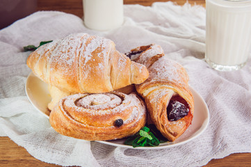 Close up continental breakfast with assortment of fresh pastries and glass of milk. Selective focus
