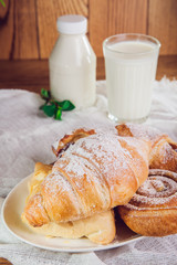 Close up plate with assortment of various fresh pastries and glass of milk on the background. Selective focus