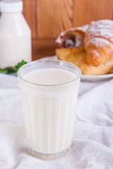Glass of milk and plate with assortment of various fresh pastries and small bottle of milk on the background. Breakfast concept, selective focus