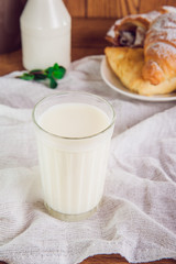 Glass of milk and plate with assortment of various fresh pastries and small bottle of milk on the background. Breakfast concept, selective focus