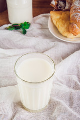Glass of milk and plate with assortment of various fresh pastries and small bottle of milk on the background. Breakfast concept, selective focus