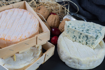 Different french soft cheeses on black stone platter