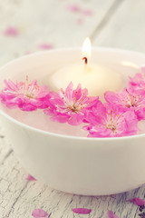 Obraz na płótnie Canvas Sakura flowers and candle in a white bowl