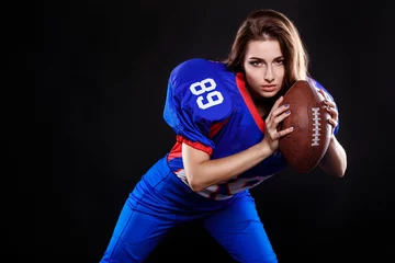 Foto op Plexiglas athletic brunette posing as american football girl on black background © selenit