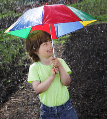 Laughing boy under an umbrella outdoor in rain