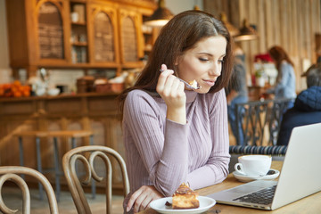 Beautiful brunette using laptop in cafe. Blogger work concept