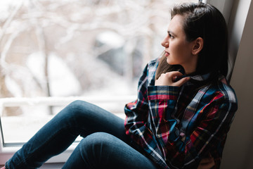 Obraz premium Beautiful young girl looking out the window contemplating