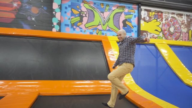  Young Men Jumping At Trampoline In Indoors Playground. Active People Male Having Fun At Sport Center. Slow Motion
