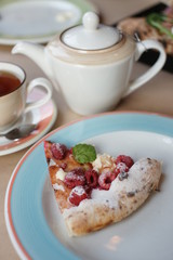 Slice of pizza with raspberries on a plate.