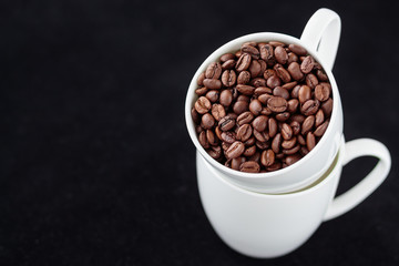 Coffee beans in coffee mug on black background. Copy space